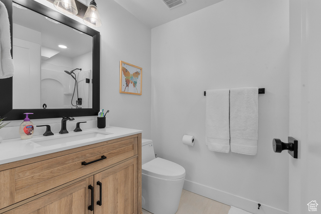 Bathroom with toilet, vanity, tile patterned flooring, a shower, and baseboards