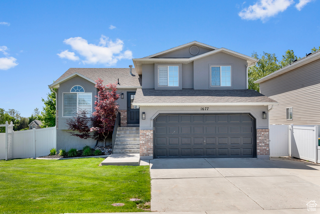 Split level home featuring concrete driveway, a garage, stucco siding, brick siding, and a shingled roof