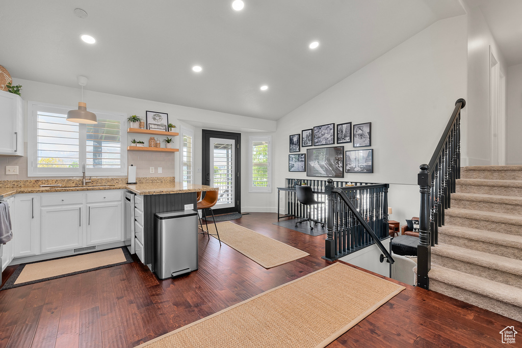 Kitchen featuring light stone countertops, white cabinets, a sink, dark wood-style flooring, and recessed lighting