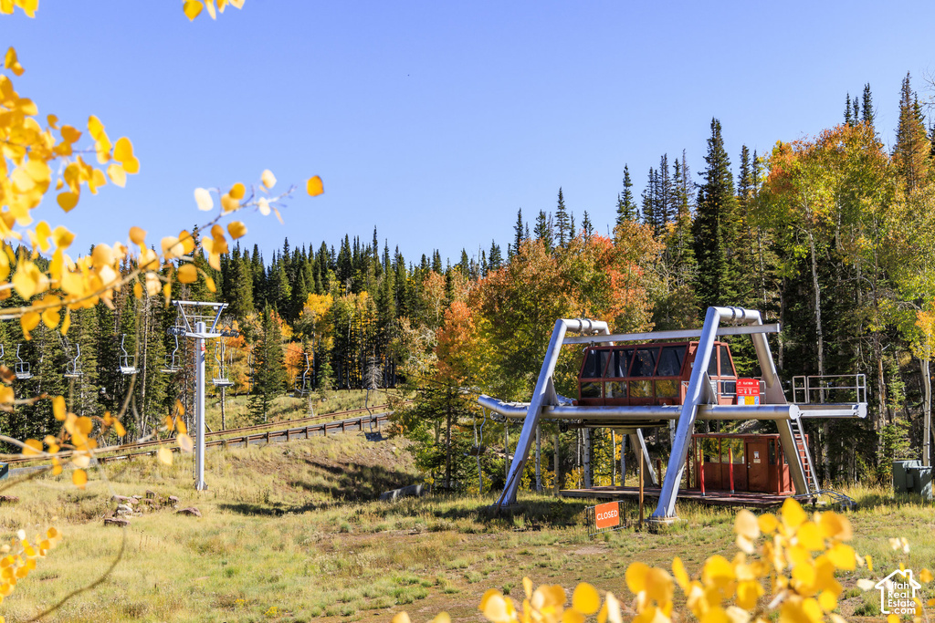 Ski lift station with a gondola and chairlift system, set against a backdrop of dense evergreen and deciduous trees with autumn foliage