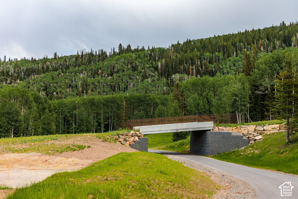 Paved road passing under a concrete bridge with a textured metal railing