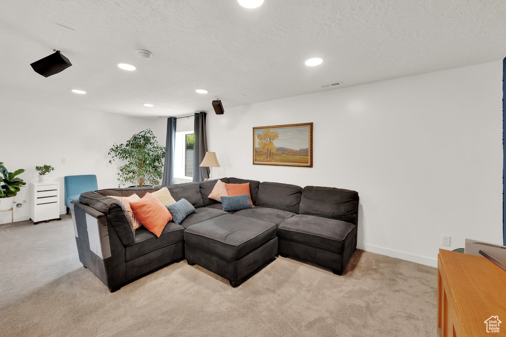 Living room featuring light colored carpet, recessed lighting, a textured ceiling, and baseboards