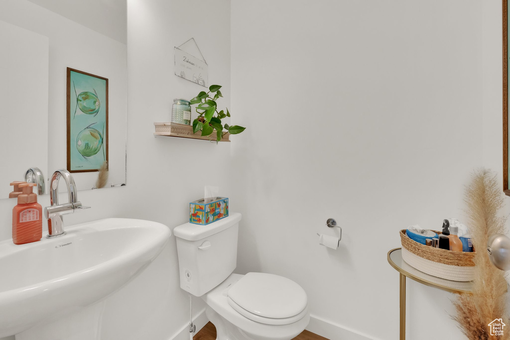 Bathroom with a sink, baseboards, toilet, and wood finished floors