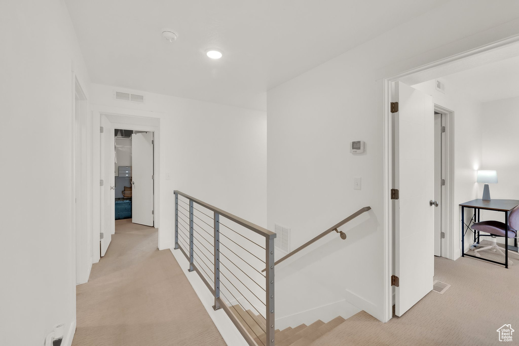 Corridor with an upstairs landing and light carpet
