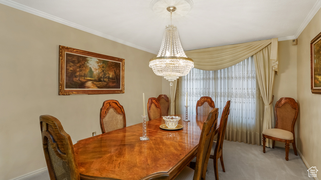 Dining space with a chandelier, light colored carpet, crown molding, and baseboards