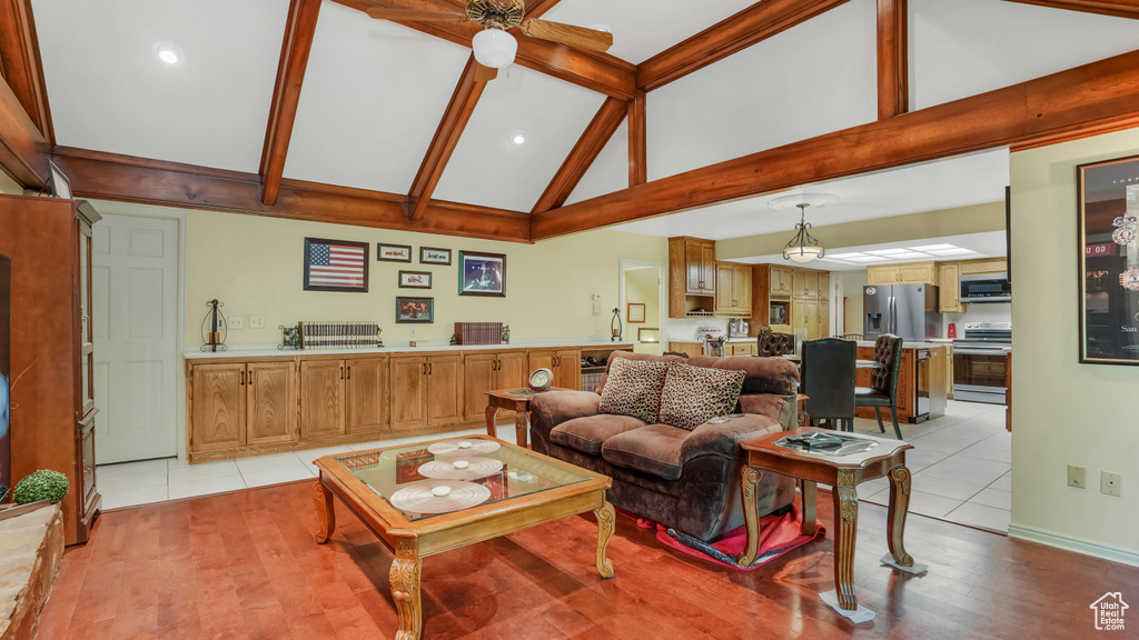 Living area featuring high vaulted ceiling, light tile patterned floors, beamed ceiling, recessed lighting, and baseboards