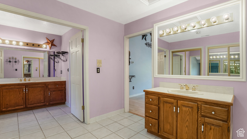 Full bathroom with two vanities, tile patterned floors, and baseboards