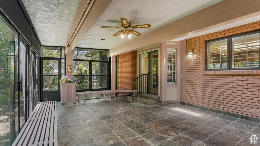 Unfurnished sunroom with ceiling fan