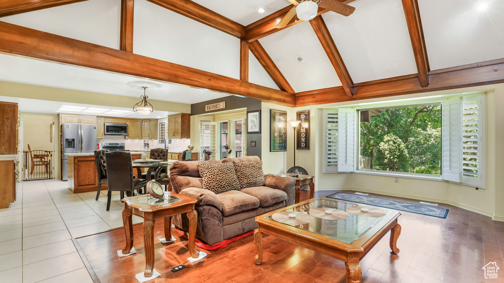 Living area with high vaulted ceiling, a ceiling fan, and beamed ceiling