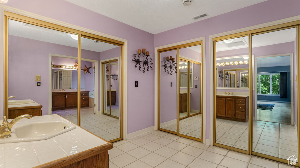 Full bath with two vanities, tile patterned flooring, and baseboards