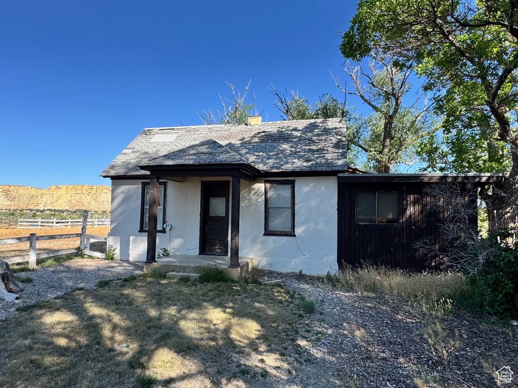 View of front of home with stucco siding and a shingled roof