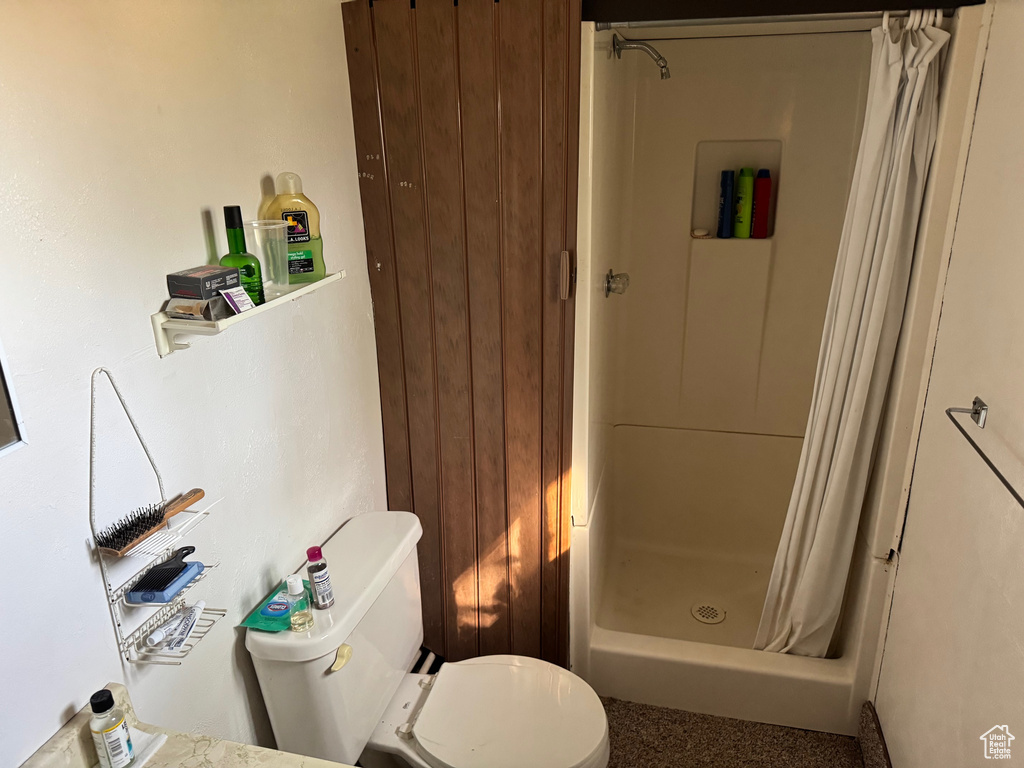 Bathroom with a shower with curtain and toilet