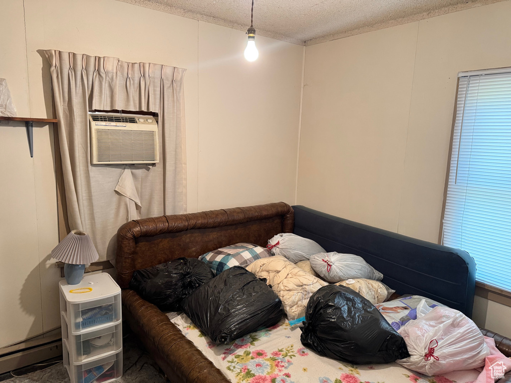 Bedroom featuring a textured ceiling, a wall mounted AC, and baseboard heating