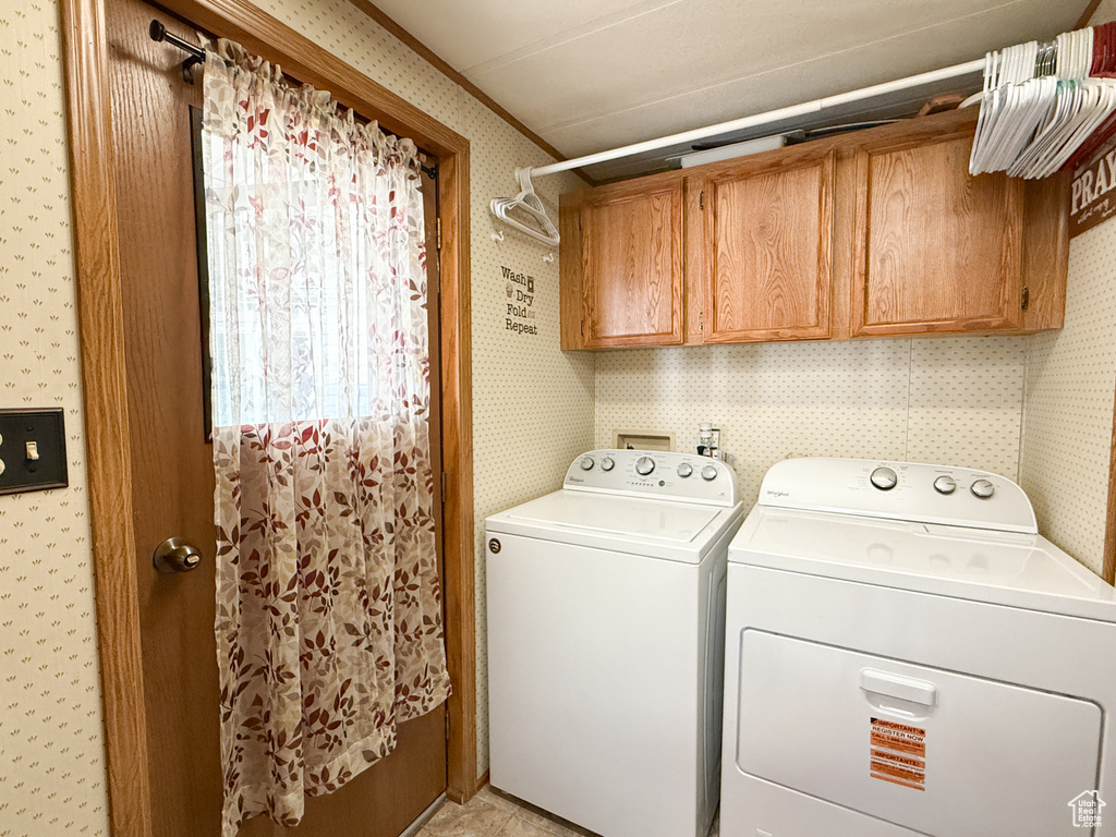 Laundry room featuring wallpapered walls, washer and dryer, and cabinet space