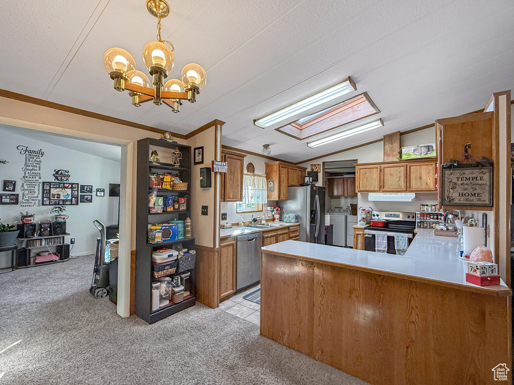 Kitchen with appliances with stainless steel finishes, light carpet, a chandelier, lofted ceiling, and washing machine and clothes dryer