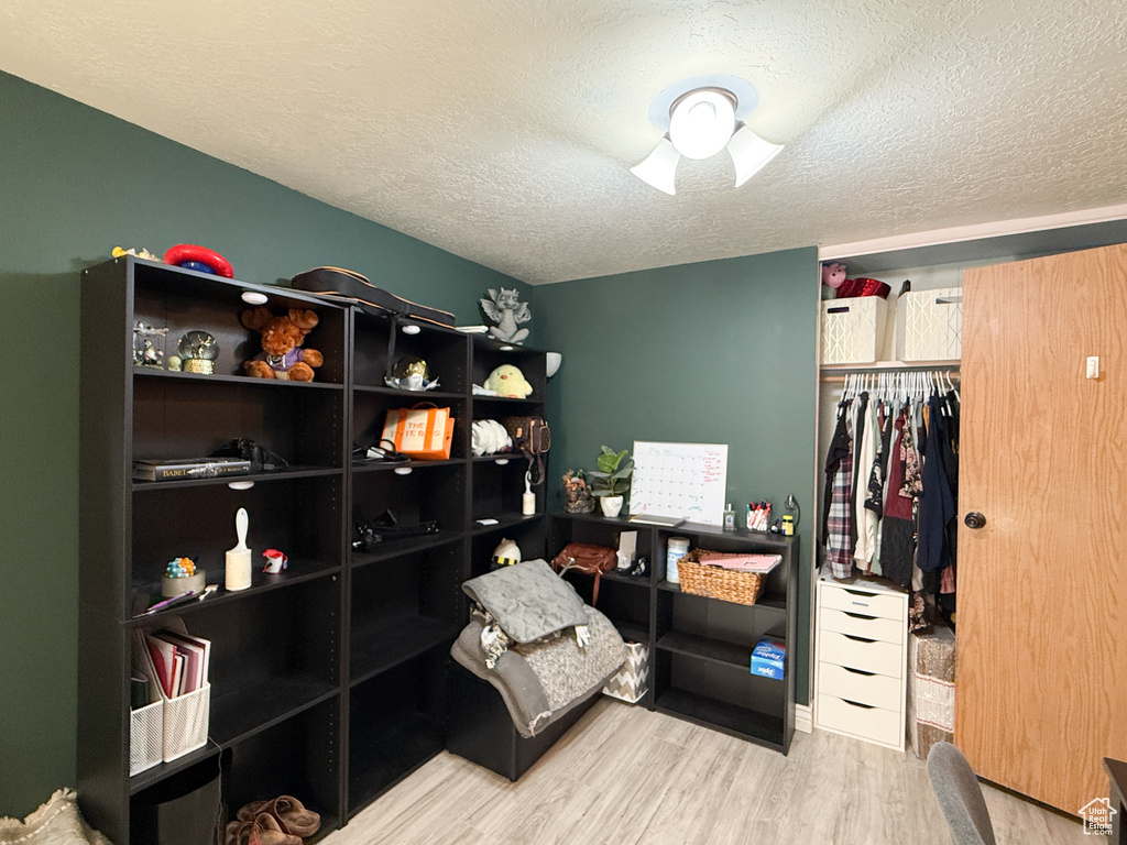 Bedroom featuring a textured ceiling, wood finished floors, and a closet