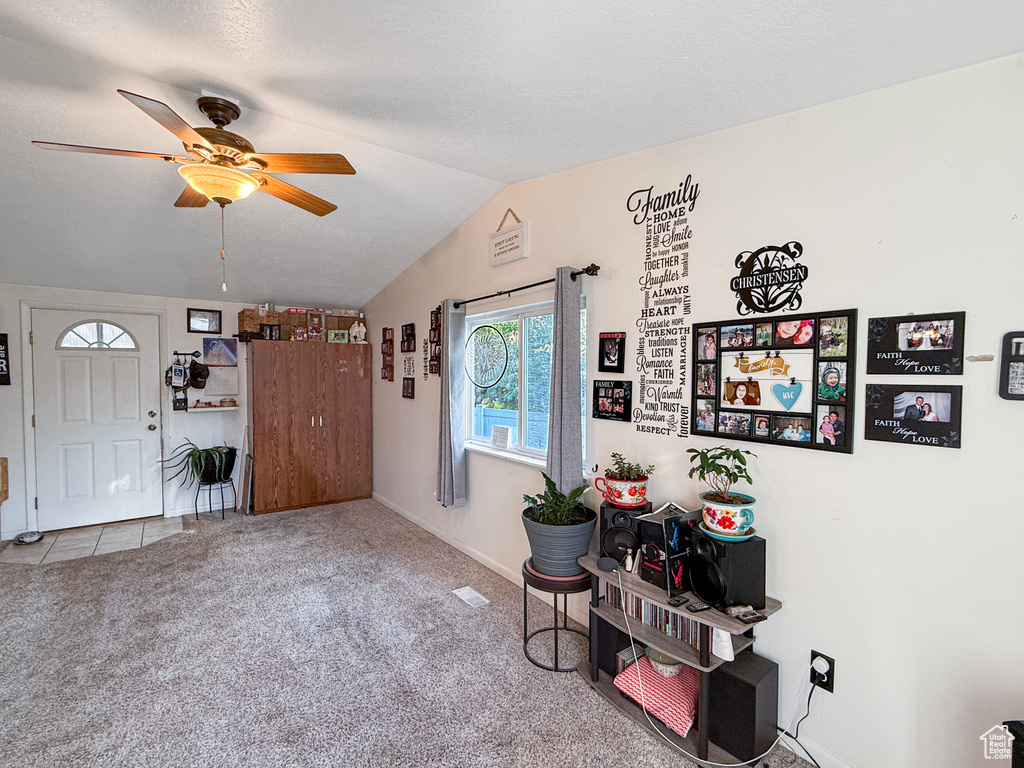 Carpeted entrance foyer featuring lofted ceiling and a ceiling fan