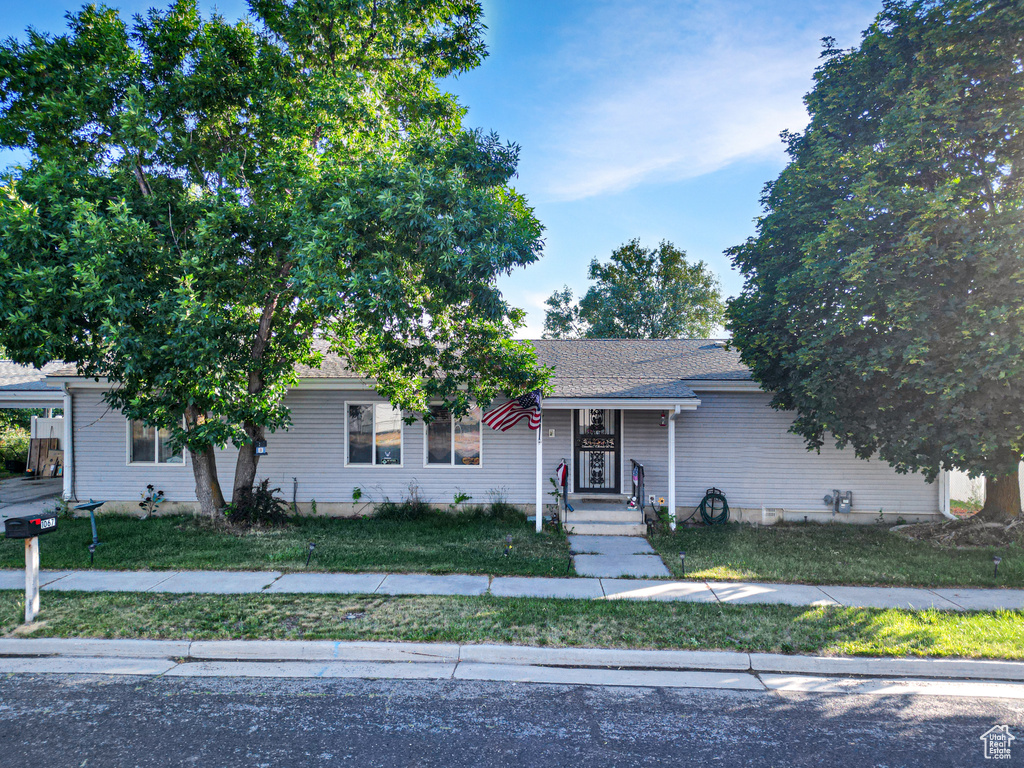 View of front facade featuring a front lawn and a carport