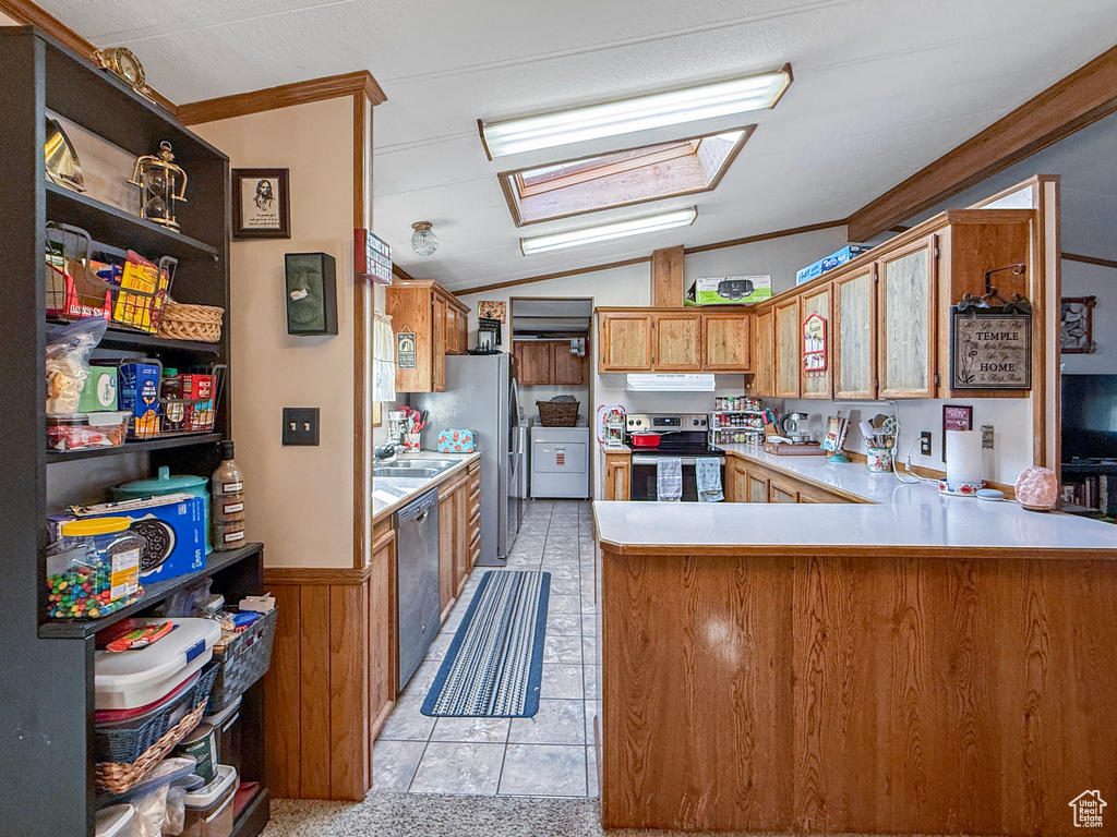 Kitchen featuring stainless steel appliances, light countertops, a peninsula, ornamental molding, and lofted ceiling