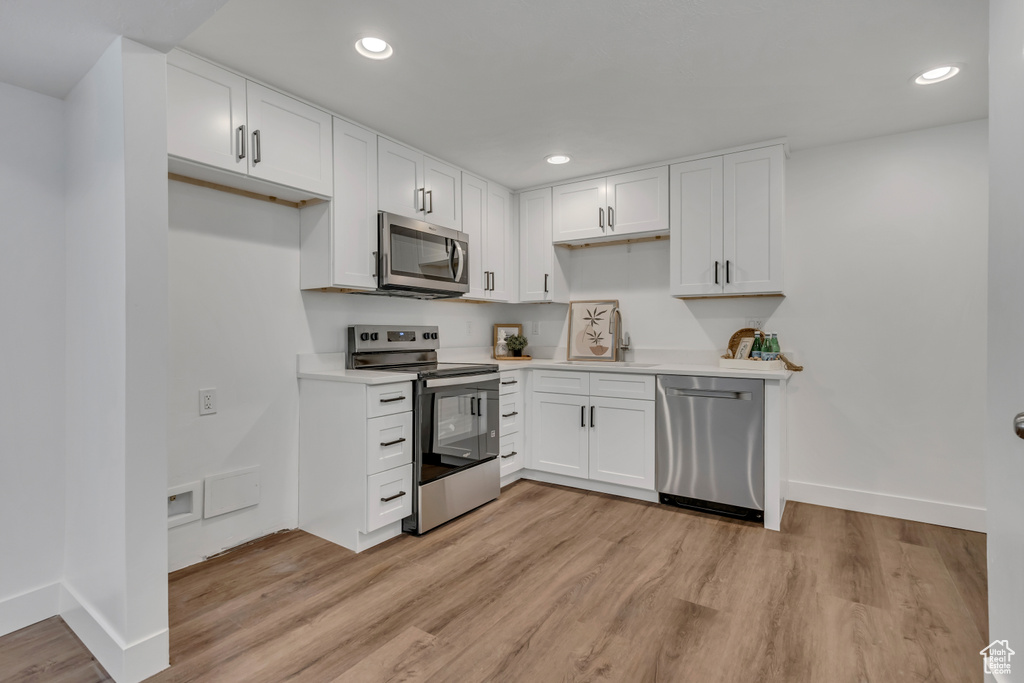 Kitchen featuring appliances with stainless steel finishes, a sink, baseboards, recessed lighting, and white cabinets