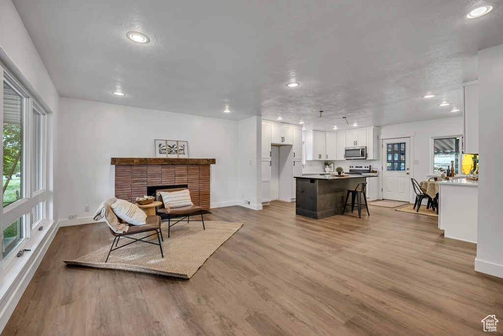 Living room with recessed lighting, baseboards, wood finished floors, and a brick fireplace