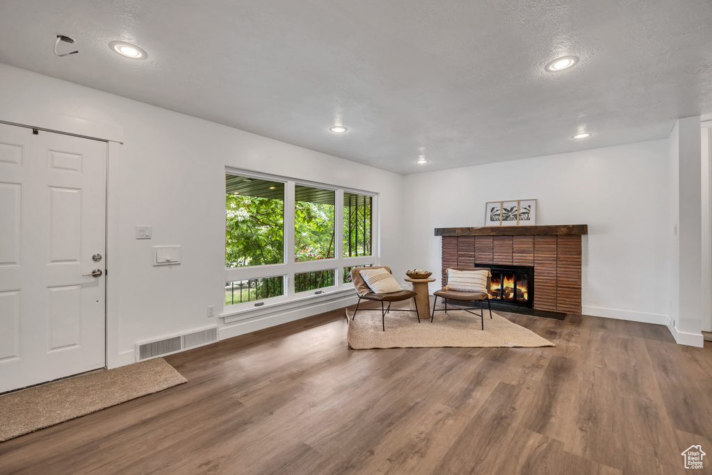 Living room featuring wood finished floors, a brick fireplace, recessed lighting, and baseboards