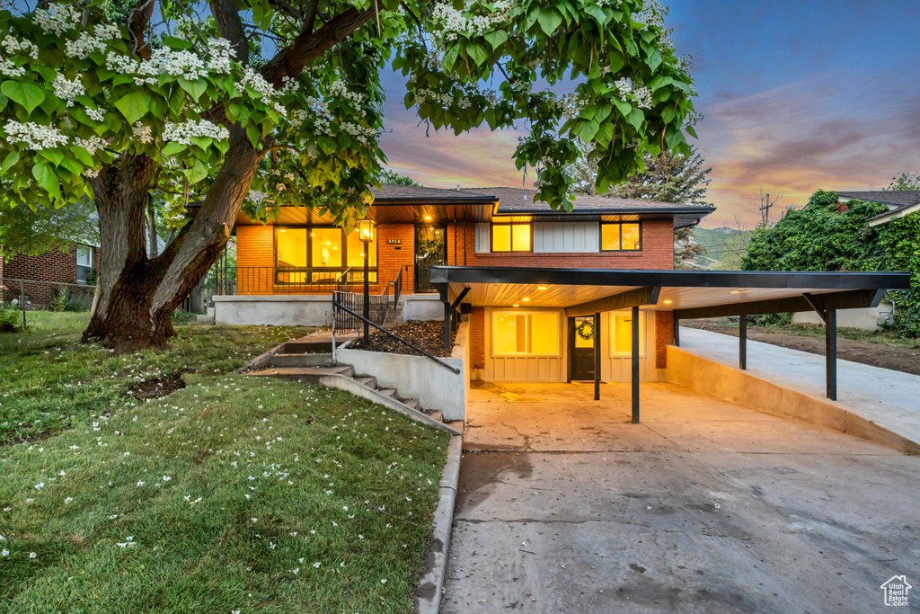 View of front of property with driveway, brick siding, and a front yard