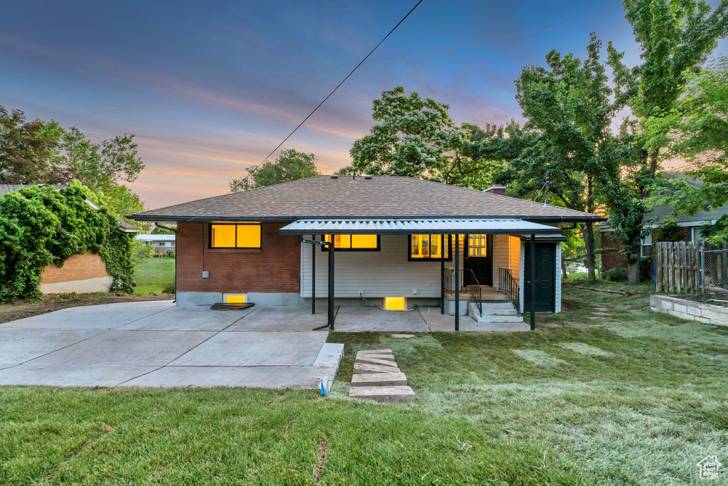 Rear view of house with a shingled roof and a patio area