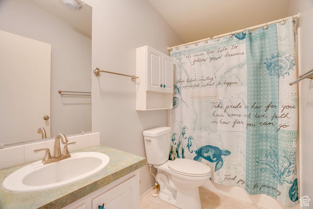 Bathroom with toilet, vanity, tile patterned flooring, and shower / bathtub combination with curtain