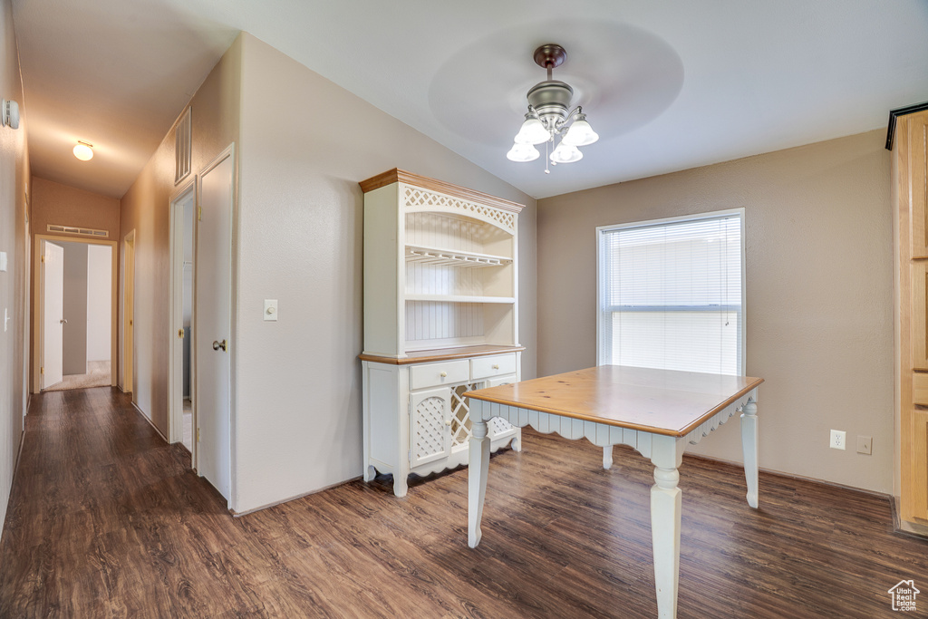 Unfurnished dining area featuring lofted ceiling, a ceiling fan, and dark wood-style floors