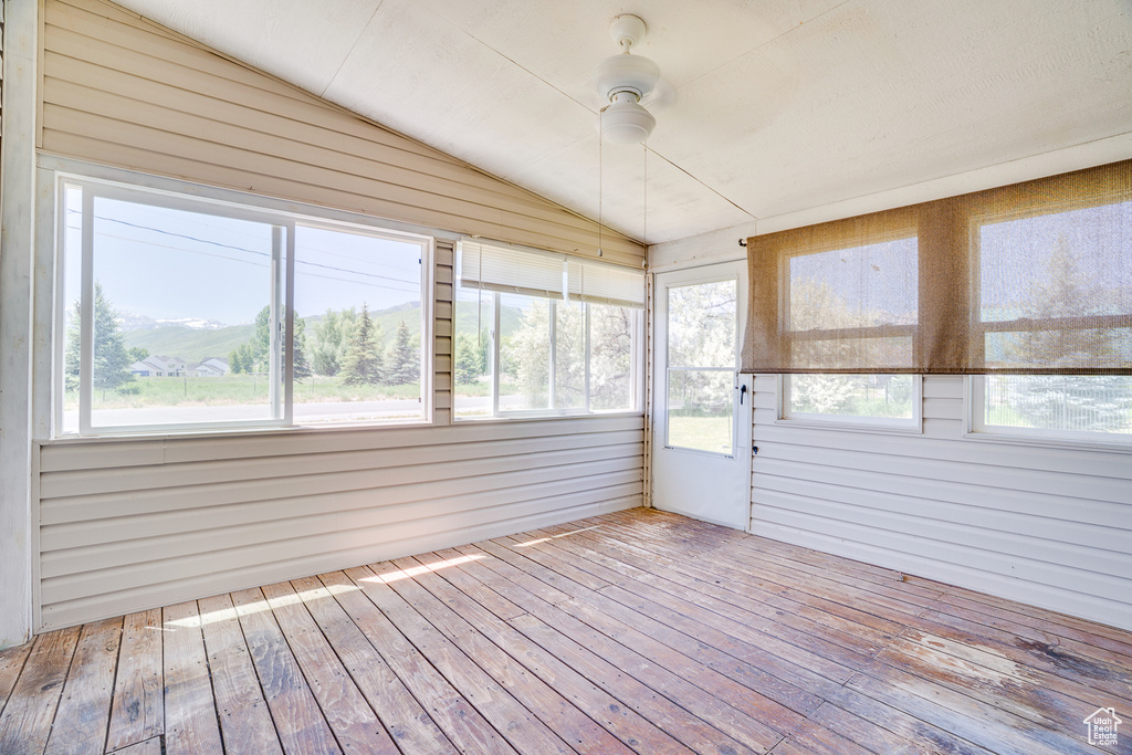 Unfurnished sunroom with lofted ceiling, a ceiling fan, and healthy amount of natural light