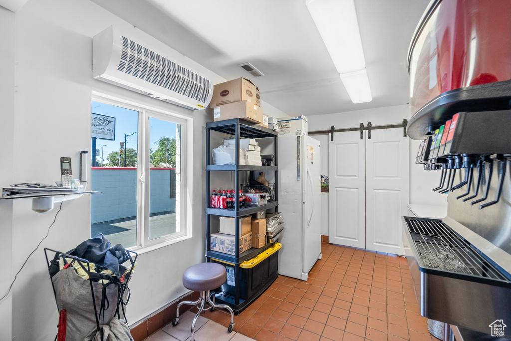 Kitchen with freestanding refrigerator, a barn door, tile patterned flooring, and a wall mounted AC