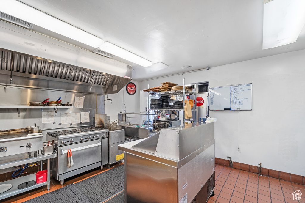 Kitchen with high end range, stainless steel countertops, dark tile patterned flooring, and baseboards