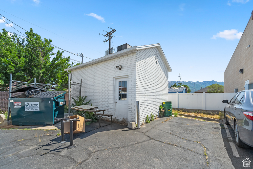 Back of house featuring a patio, a mountain view, brick siding, and uncovered parking