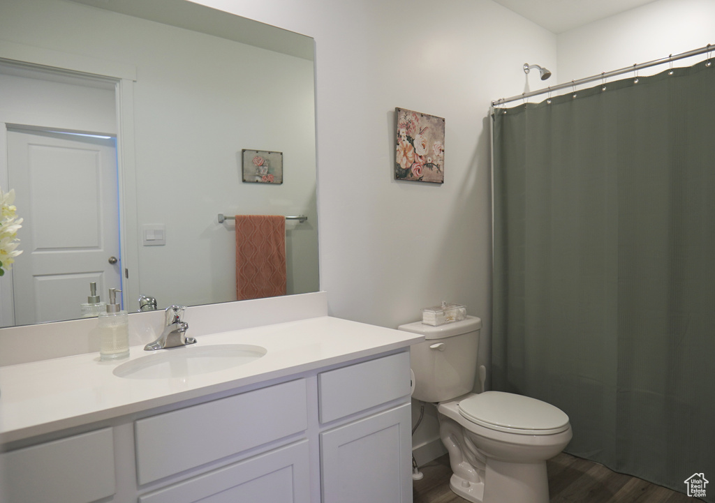 Full bath featuring wood finished floors, vanity, toilet, and curtained shower