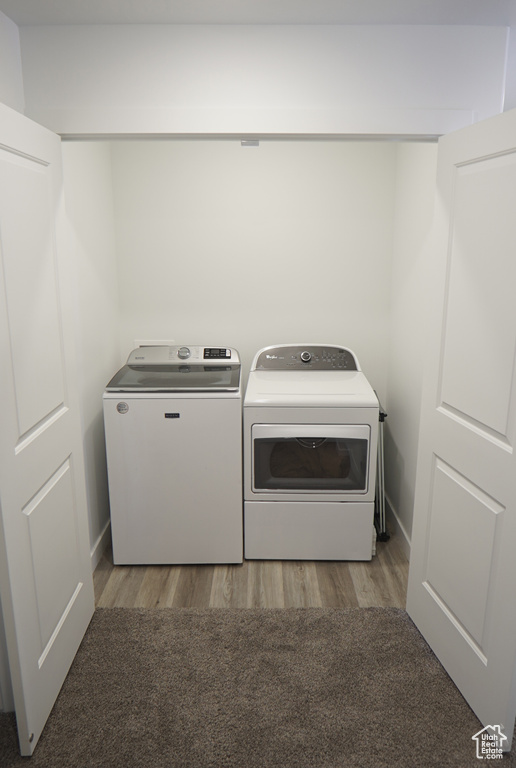 Laundry room featuring washer and clothes dryer, wood finished floors, and baseboards