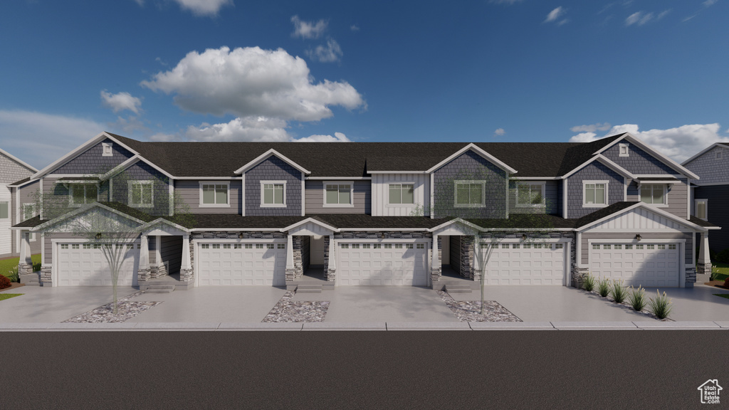 Townhome / multi-family property with stone siding, driveway, board and batten siding, and a garage