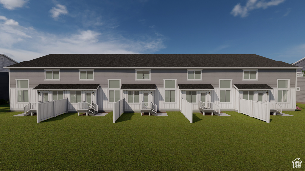 Back of house with a lawn and a shingled roof