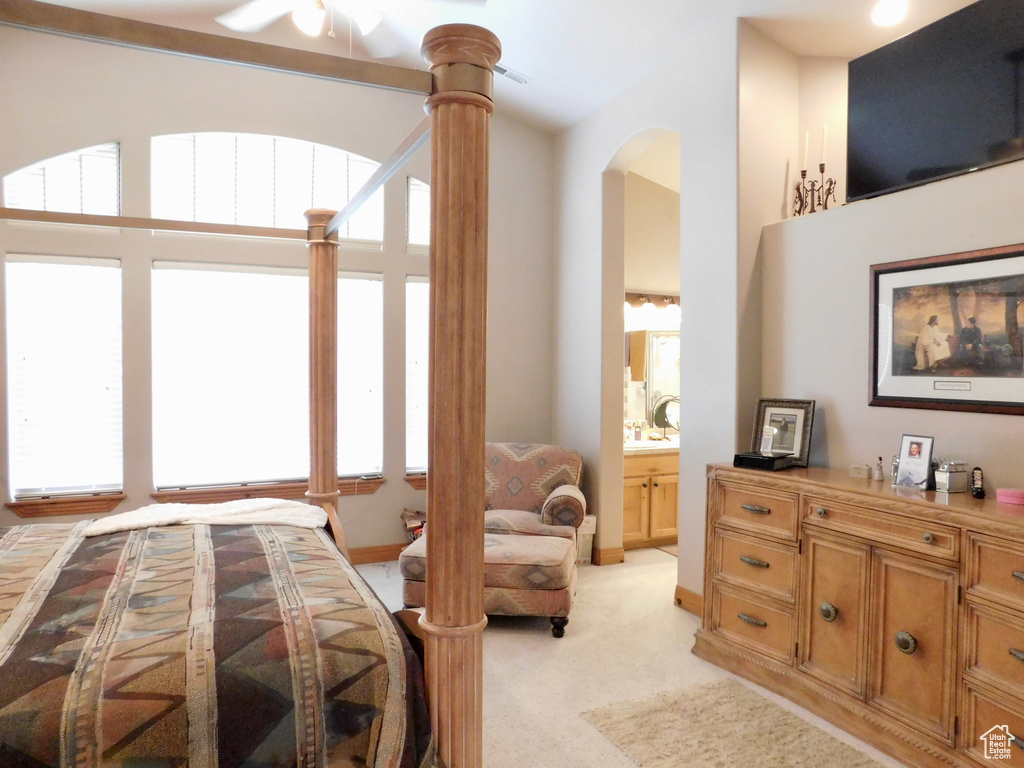 Bedroom with light colored carpet, arched walkways, ensuite bath, and baseboards