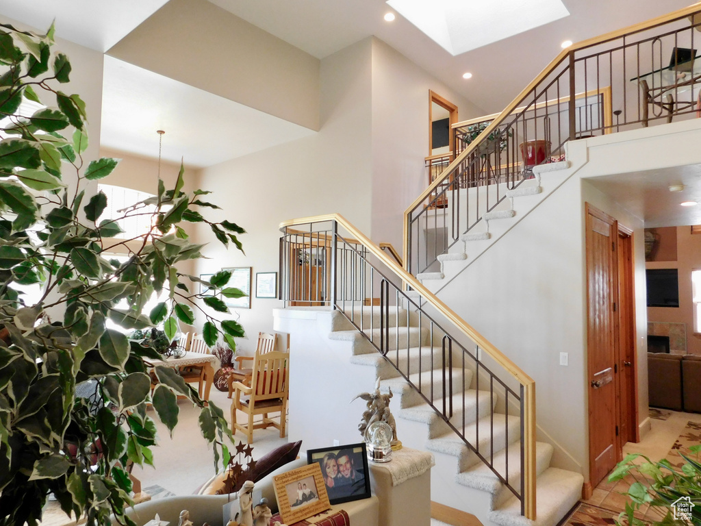 Staircase with a skylight, recessed lighting, and a high ceiling