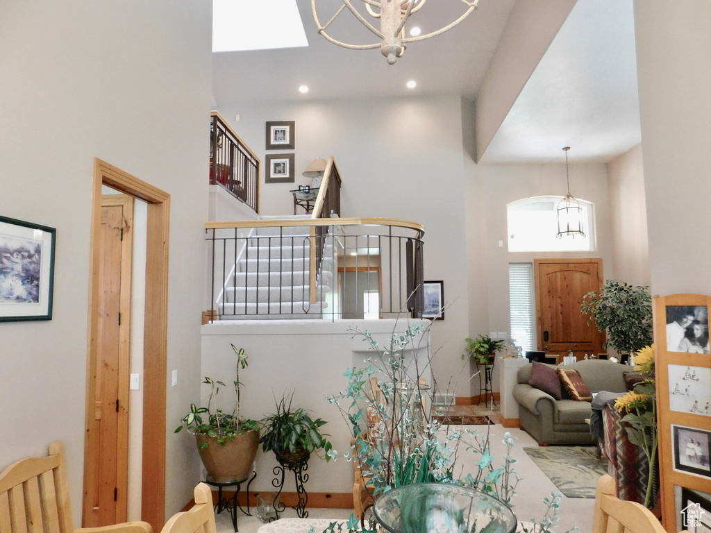 Living room with a towering ceiling, stairway, a chandelier, recessed lighting, and baseboards