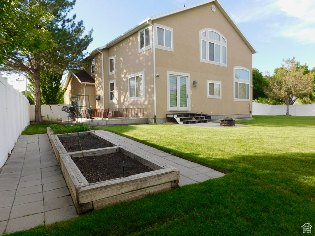 Back of house with a vegetable garden, stucco siding, a fire pit, and french doors