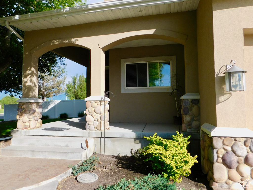 Doorway to property with stucco siding and covered porch