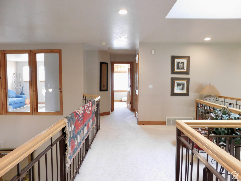 Corridor with an upstairs landing, light colored carpet, baseboards, and recessed lighting