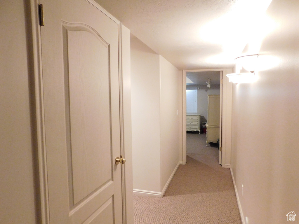 Hall with light colored carpet and baseboards