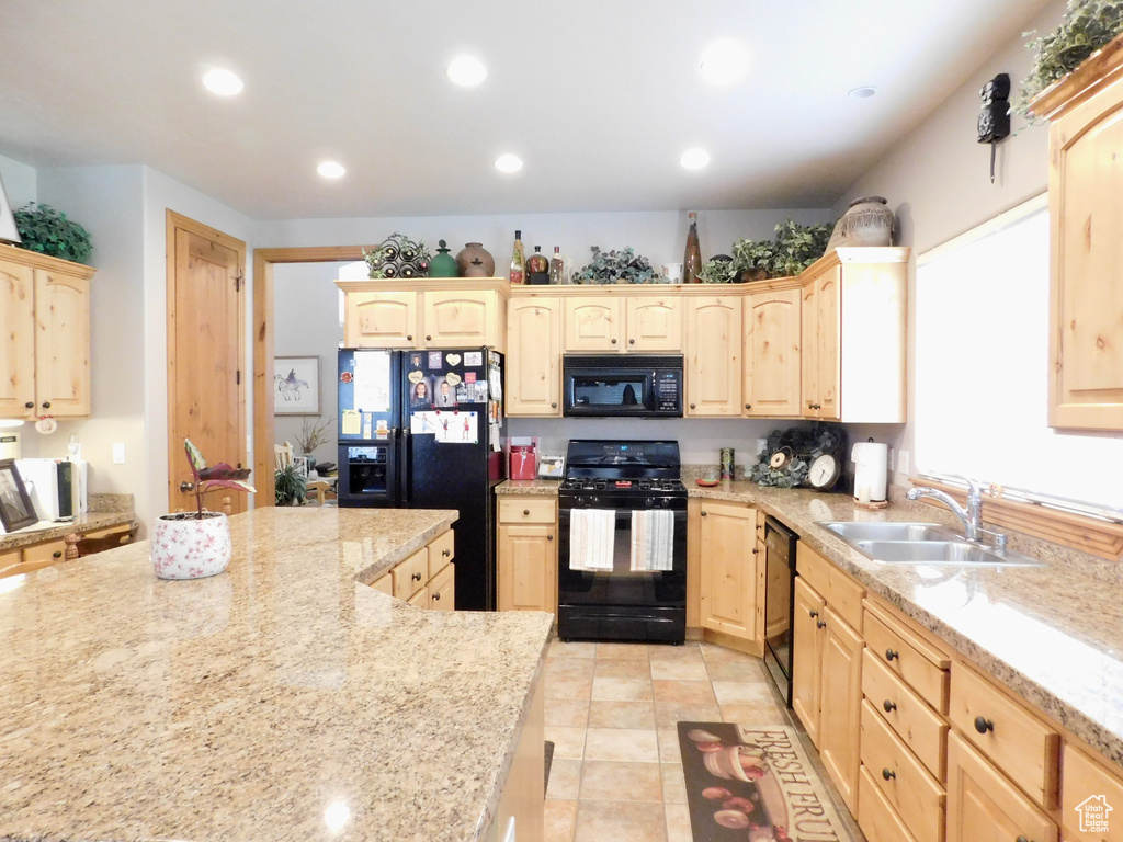 Kitchen featuring black appliances, light brown cabinetry, a sink, recessed lighting, and light stone countertops