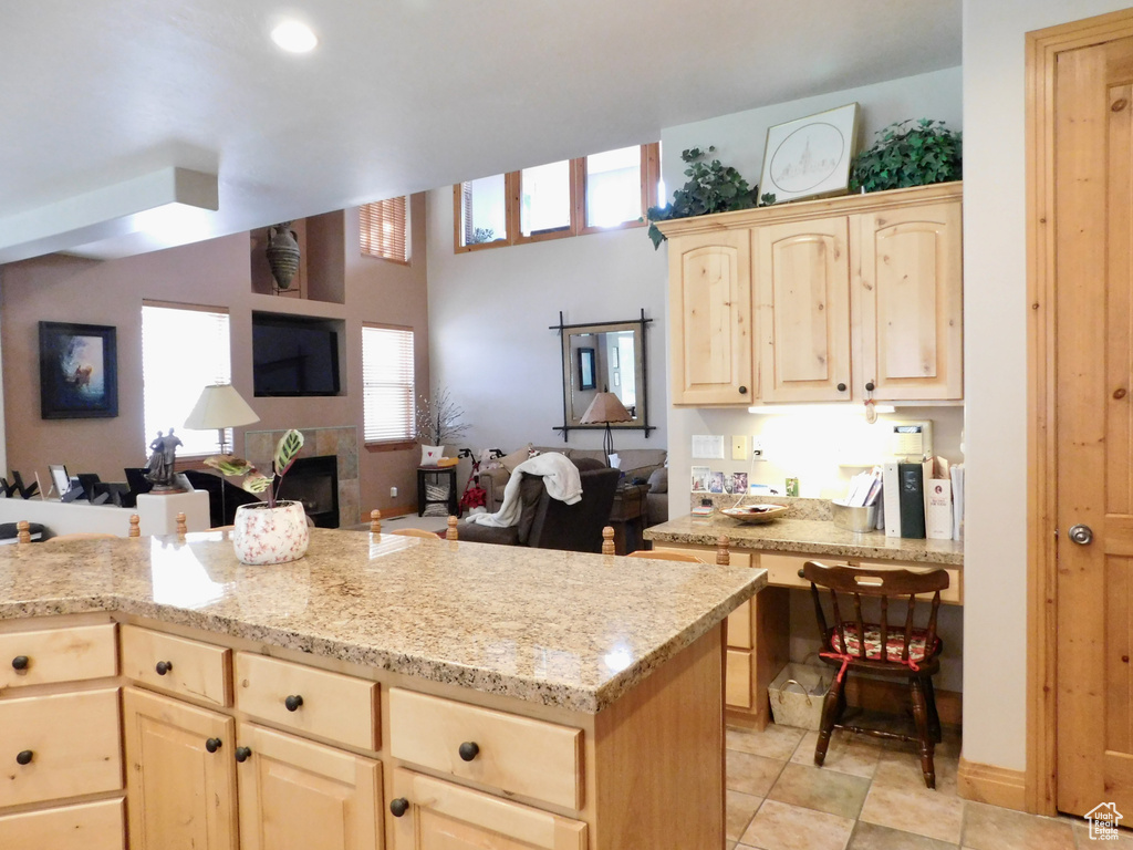 Kitchen featuring light brown cabinets, open floor plan, and light stone counters