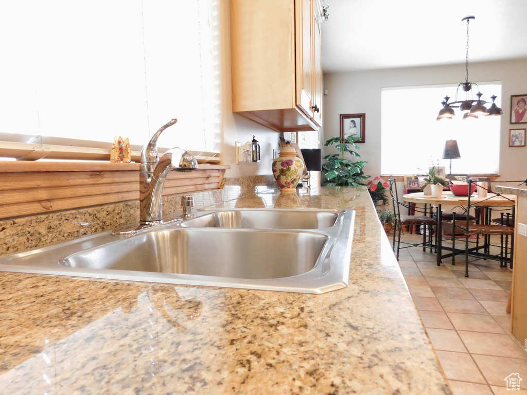 Kitchen with a sink, light countertops, light tile patterned floors, decorative light fixtures, and light brown cabinetry