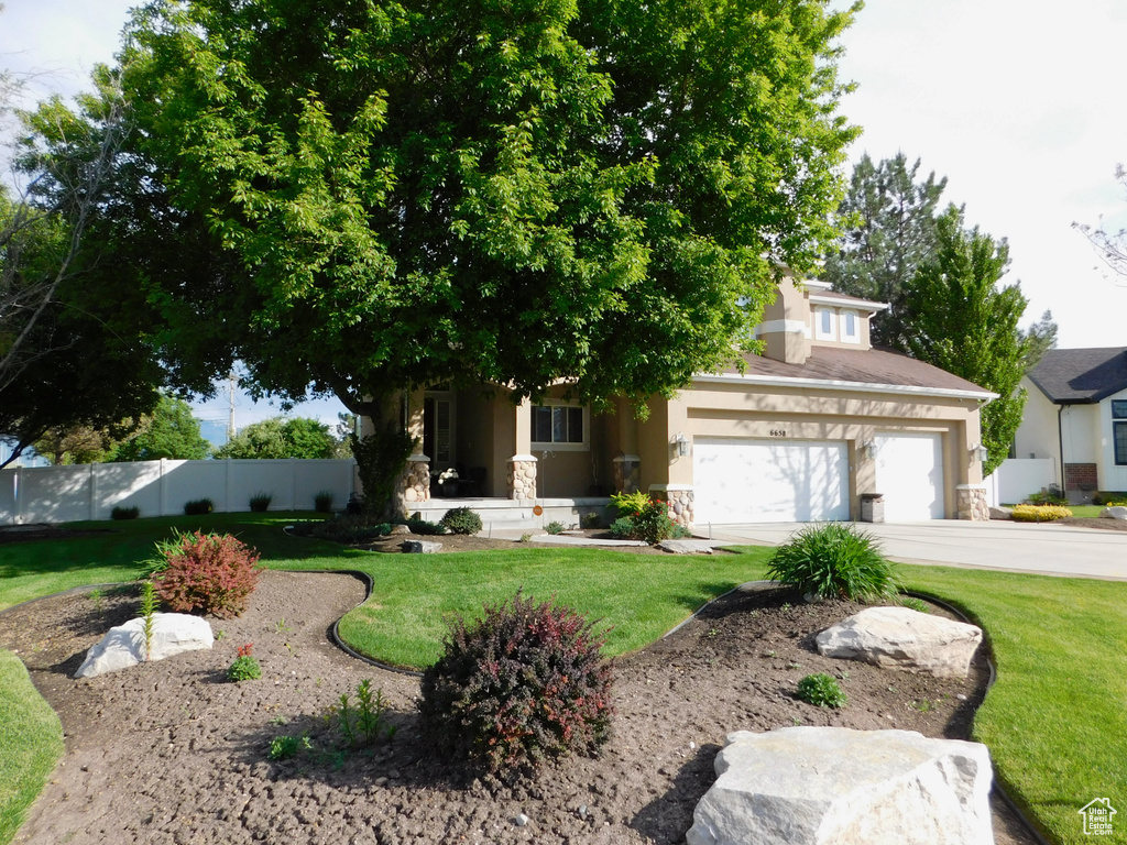 Obstructed view of property featuring stone siding, stucco siding, driveway, and an attached garage