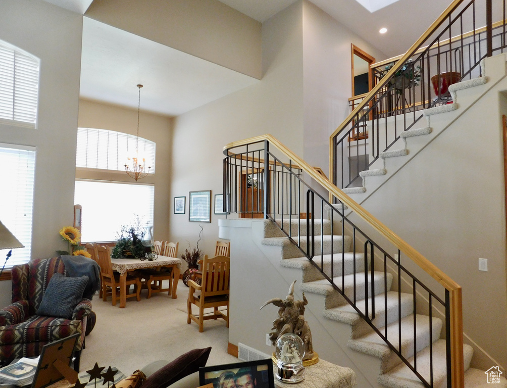Stairway with carpet, a chandelier, recessed lighting, and a high ceiling